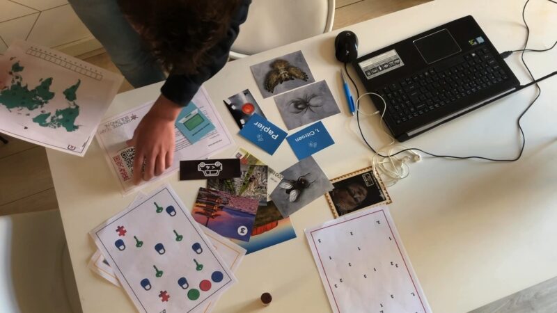 Remote Teambuilding online teambuilding van The Box Company spelattributen op tafel naast laptop