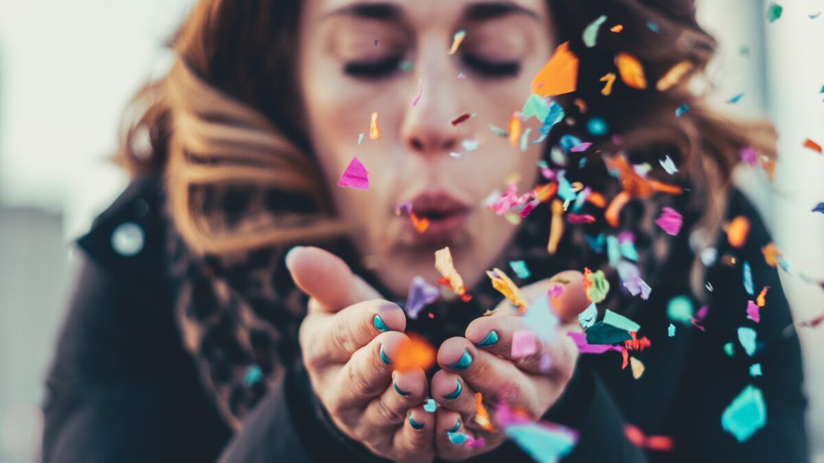 Vrouw die confetti wegblaast uit haar handen