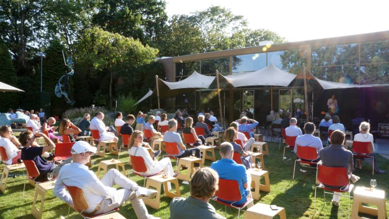 Coronaproof bijeenkomst in de tuin van Singer Laren met rode stoeltjes en een stretchtent