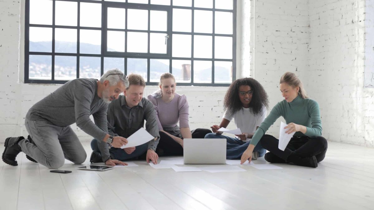 Diversiteit - 5 mensen voor een laptop die zitten op de grond tijdens een brainstorm : vergadering