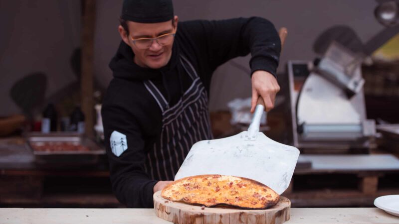 Event Inspiration - Kok bij Buiten in de Kuil die een pizza op een houten plank legt