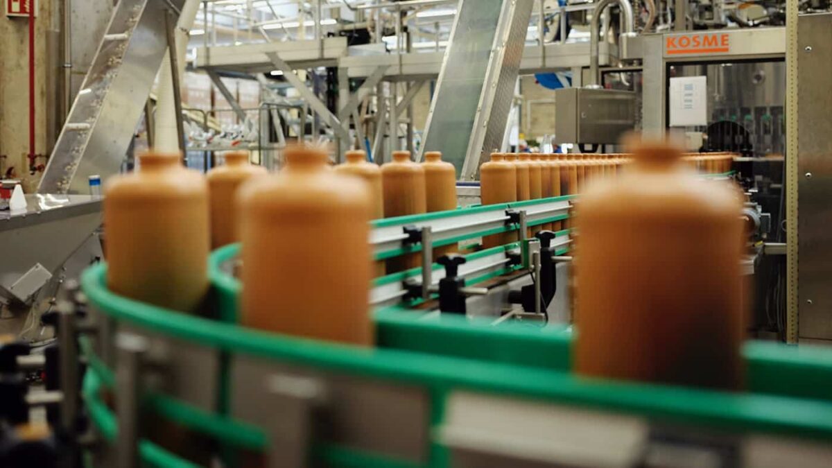 Fabriek met een lopende band waar bruine jeneverflessen op staan