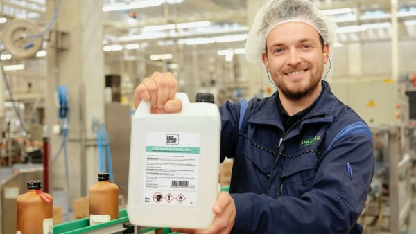 Keep Hands Clean handalcohol jerrycan vastgehouden in een fabriek door een medewerker