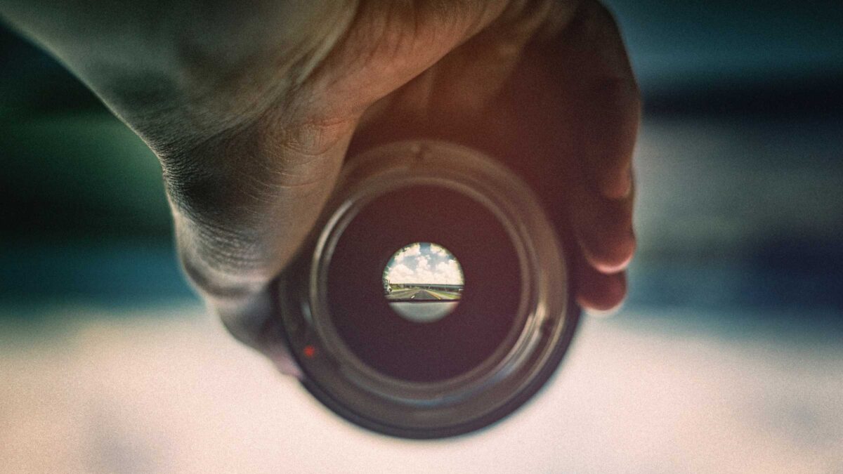 Man houdt lens vast waardoor je ver weg scherp ziet en eromheen vaag - Focus om een goed concept te bedenken