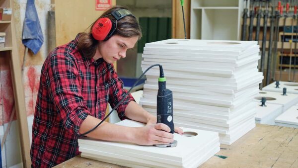 Medewerker van een fabriek die rondjes zaagt uit panelen