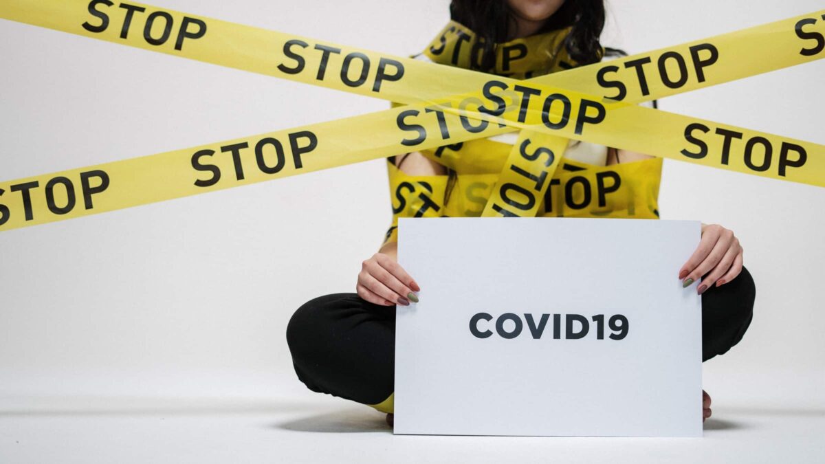 Vrouw met lint met stop erop en bord covid19