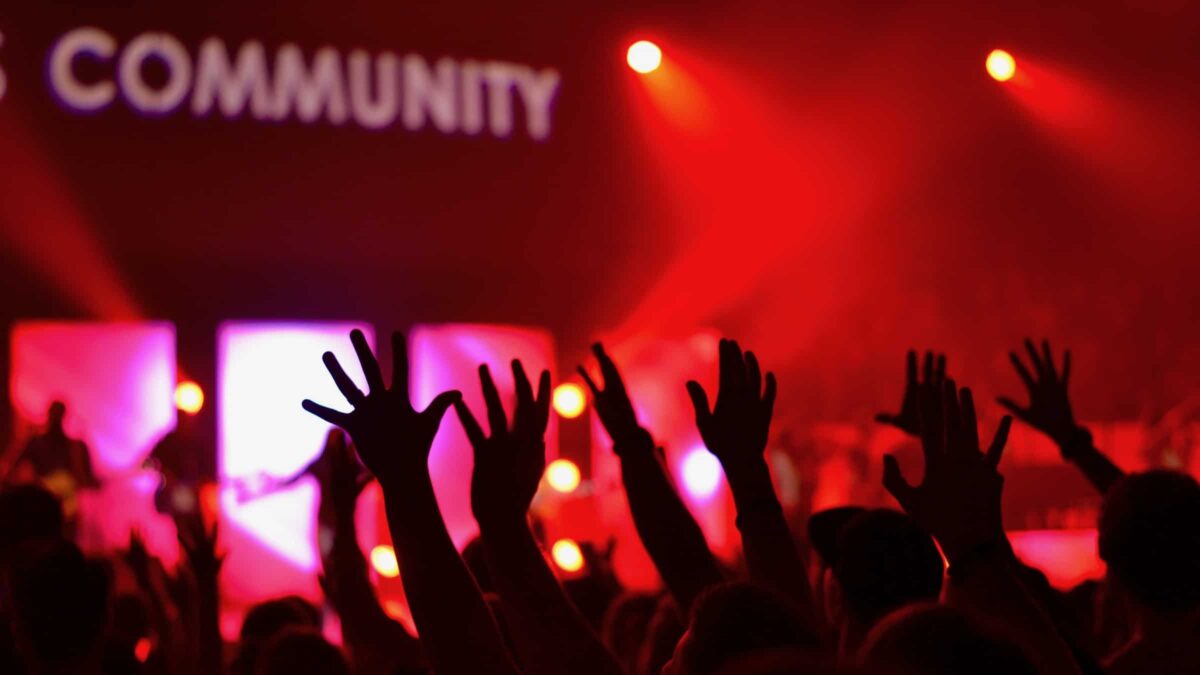 woord community met mensen in een zaal die hun handen omhoog doen