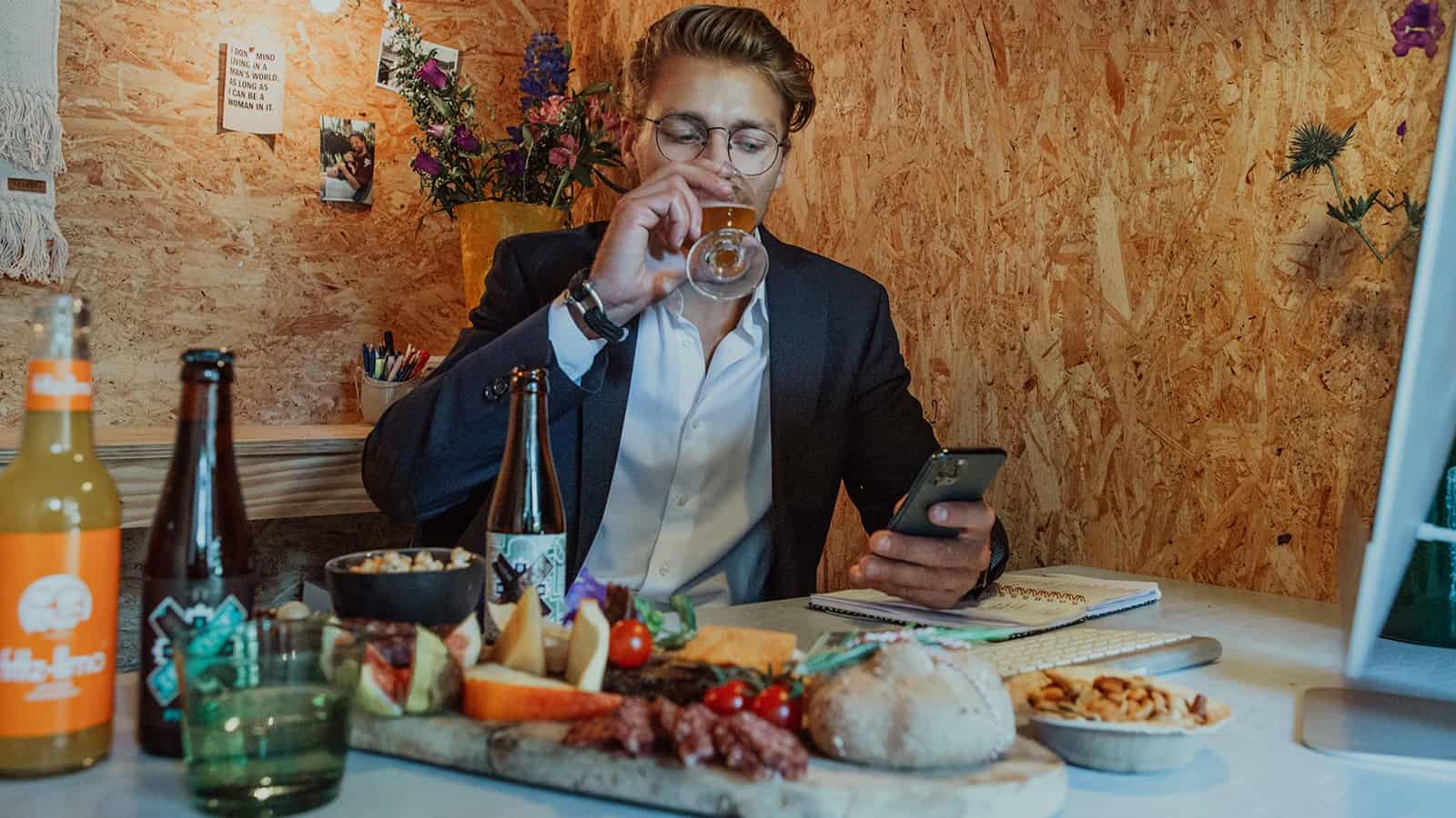 Man die een biertje drinkt tijdens een online meeting met een borrelplank ernaast van Caterbox