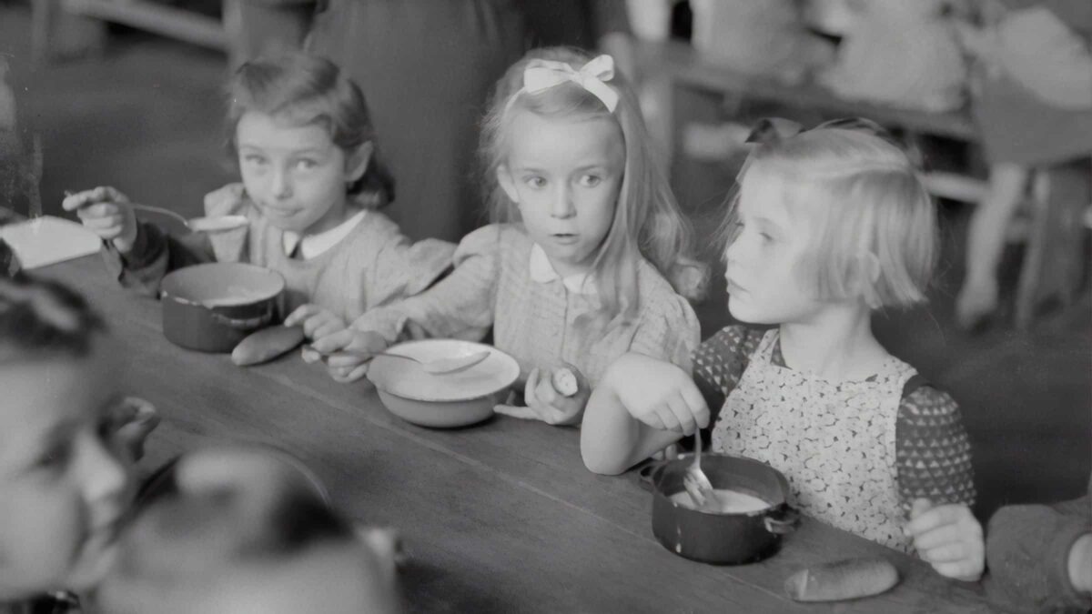 Foto van vroeger met 3 meisjes die pap eten uit een kommetje