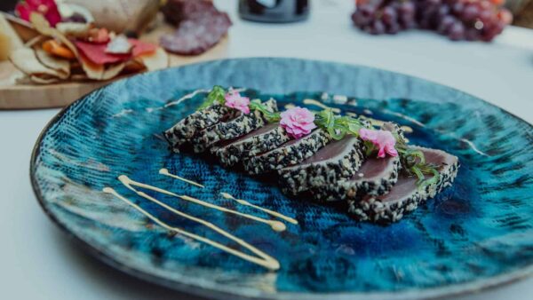 Gerecht met tonijn en bloemen op een blauw bord