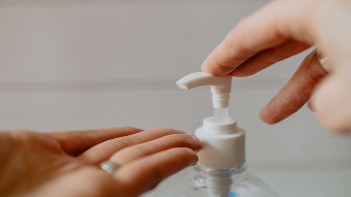 Handen die desinfecterende handgel pakken om corona tegen te gaan