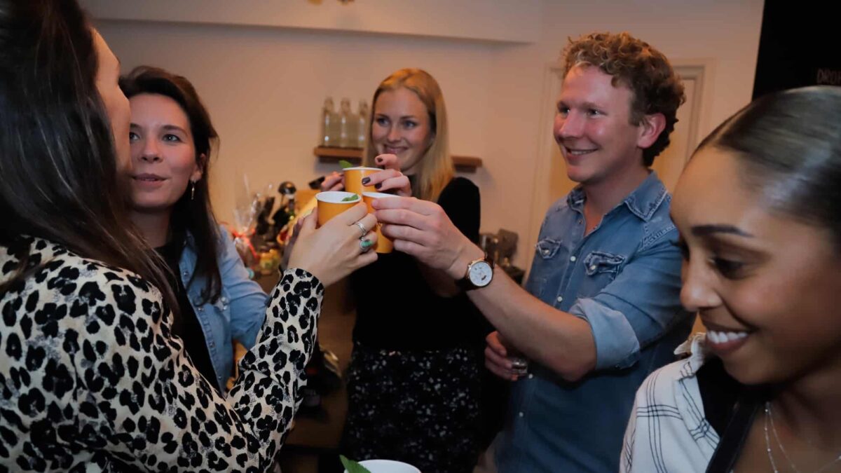 Vijf mensen die proosten met gele kartonnen bekers