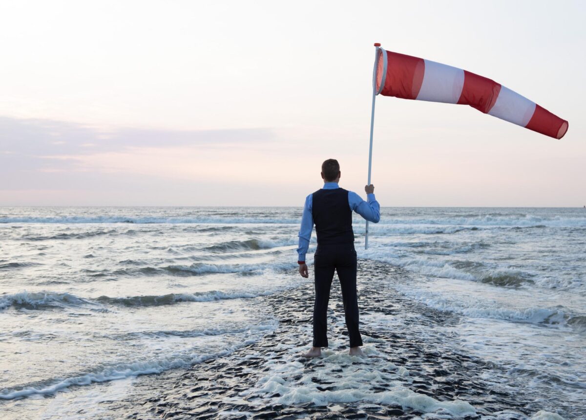 Man met windvlag met voeten in de zee