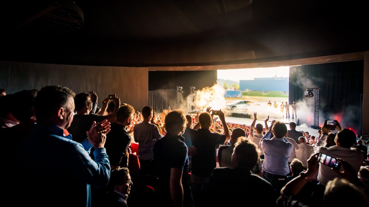 Plugged Live Shows optreden in zaal met auto op het podium en veel mensen