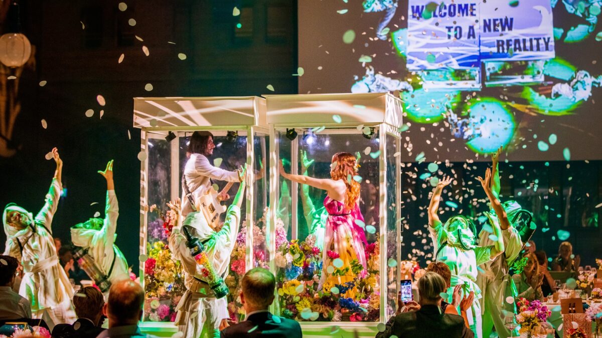 Plugged Live Events mensen in doorzichtige kooien met bloemen en dansers eromheen