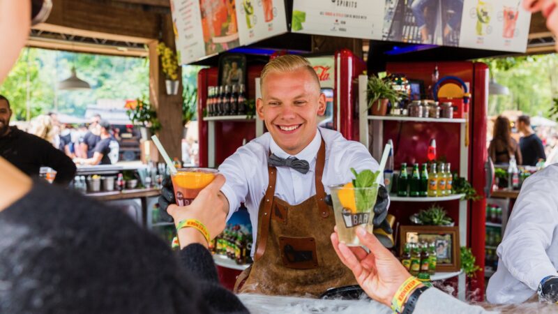 Lachende medewerker bij de bar tijdens Mysteryland