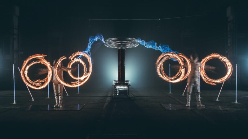 Twee mensen die vuur ronddraaien en electriciteit erachter tijdens Tesla event