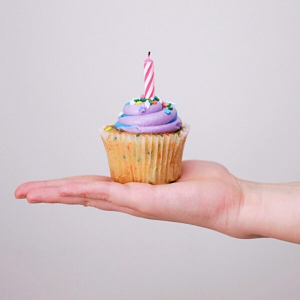 Cakeje met kaarsje op iemand hand