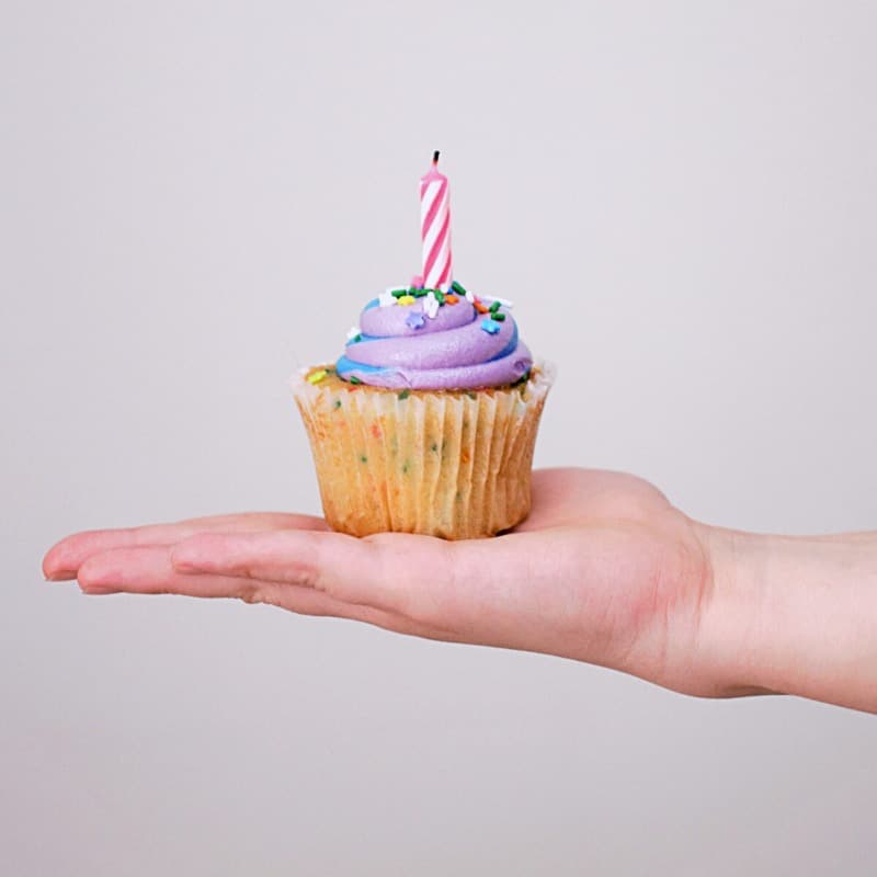 Cakeje met kaarsje op iemand hand