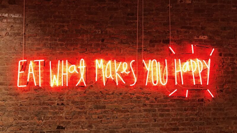 Lichtgevende letters met de zin eat what makes you happy (Foto- Jon Tyson)