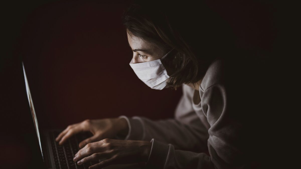Vrouw met mondkapje achter laptop