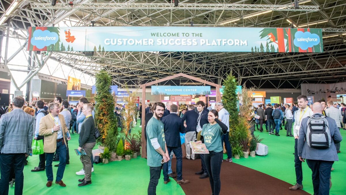 Beurs van Salesforce met stands, mensen en grote banner met customer success platform