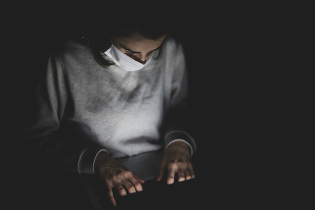 Man met mondkapje op laptop