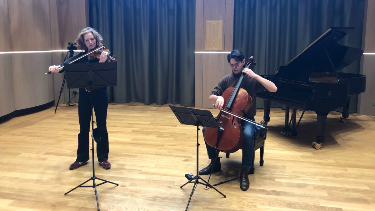 Optreden violist en cellist met piano op de achtergrond