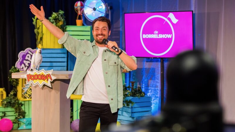 Presentator-tijdens-de-borrelshow-met-roze-scherm-achter-zich (Foto: Twycer)