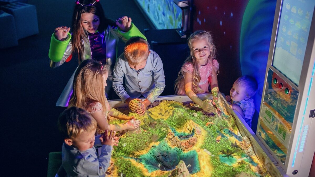 Kinderen die spelen met een interactieve zandbak met projecties