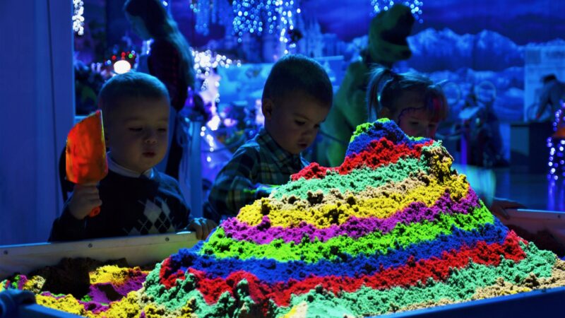 Kinderen die spelen met interactieve zandbank in regenboogkleuren
