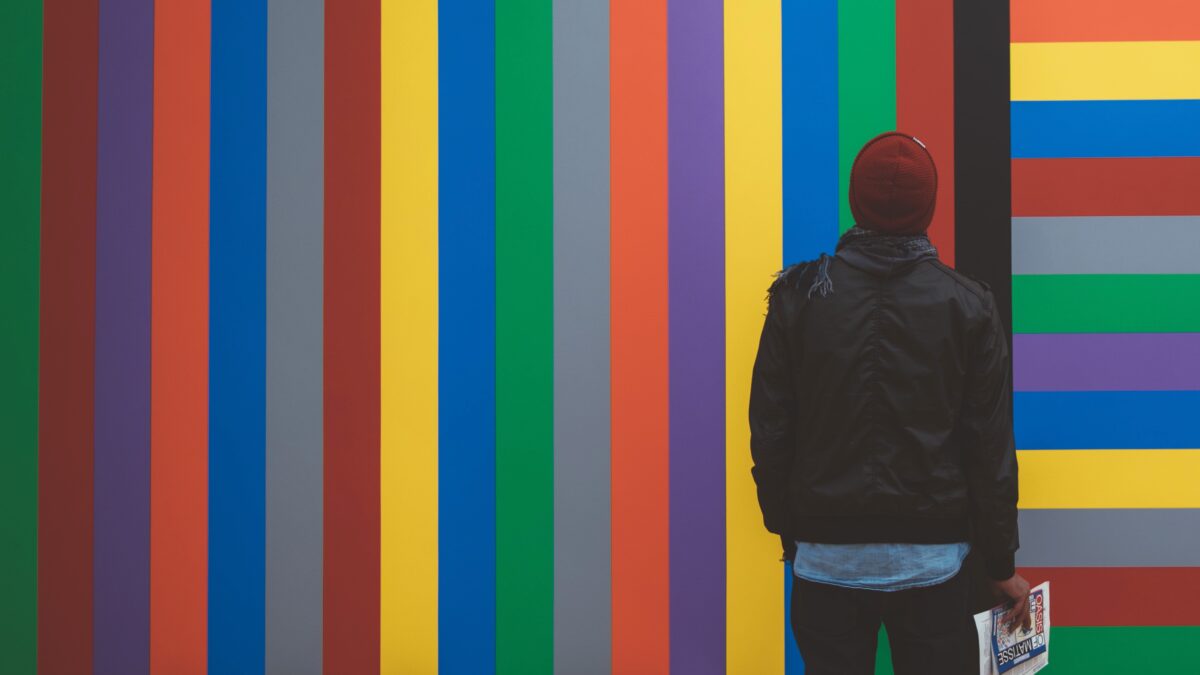 Man die staat voor een muur met gekleurde strepen - diversiteit