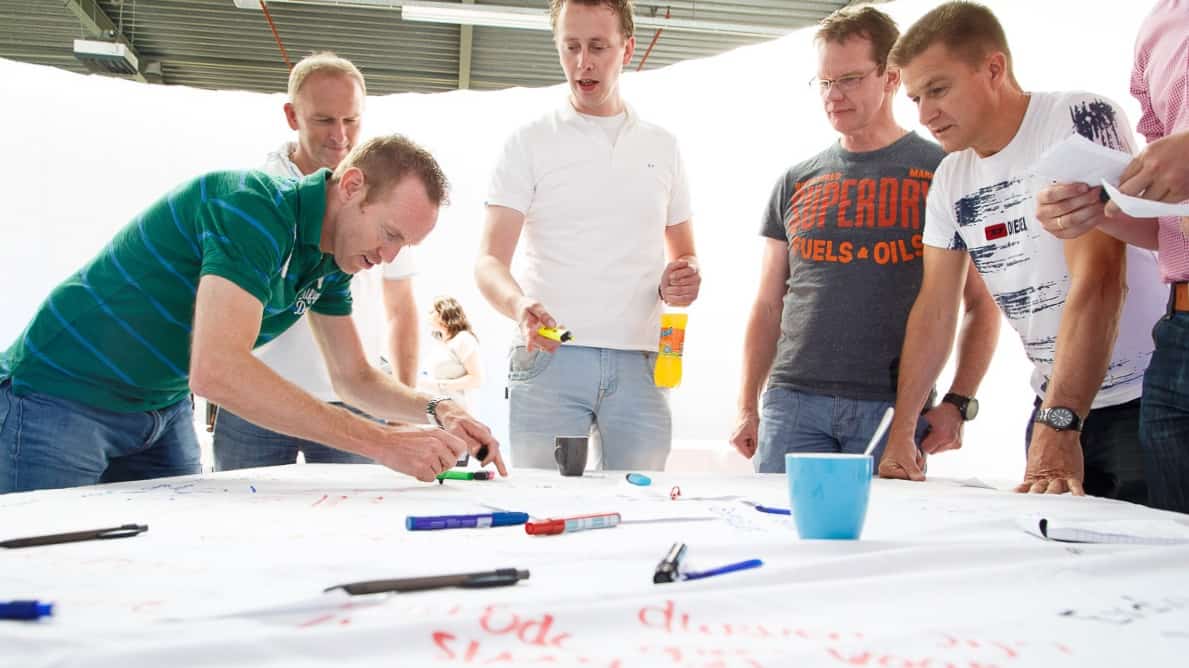 Het nieuwe werken op kantoor brainstorm met groepje mannen bij wit vel met stiften (foto - Tychos Eye)
