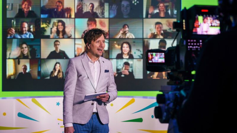 Presentator-Klaas-met-zoom-scherm-achter-zich-tijdens-online-event-Baker-Tilly-foto-Tychos-Eye-Photography