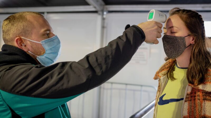 Resultaten Fieldlab testevent vrouw wiens temperatuur wordt gemeten door beveiliger