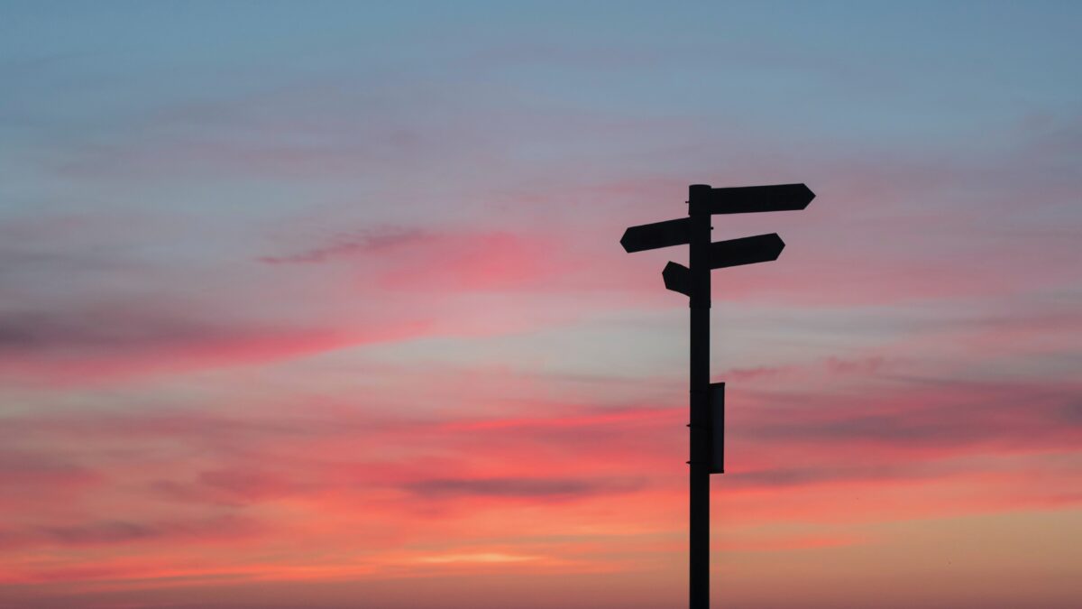 wegwijsbordjes in zwart met een zonsondergang op de achtergrond