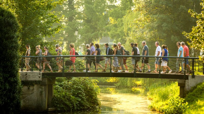Buro Curious - mensen die op een brug door een park lopen met een koptelefoon op