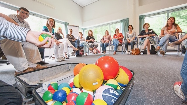 More Balls Than Most - ballen in een koffer bij mensen in een kring
