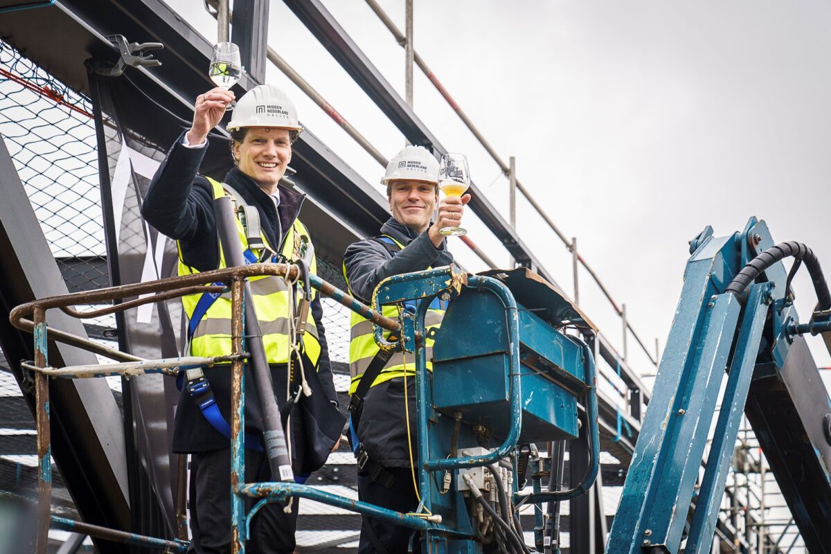 Jacco van der Tak (burgemeester gemeente Barneveld) en Timo Kruft (eigenaar Midden Nederland Hallen) brengen een toost uit op het bereiken van het hoogste punt van de nieuwe theaterhal